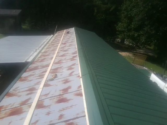 Old rusted panels beside newly installed green metal roofing — Wind Damage Roof Repair by Roofing Brothers in Baldwin Park