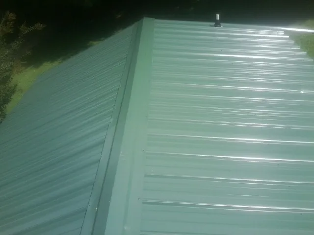 New green metal panels meeting at the ridge of a roof — Flat Roof Repair work by our crew in Baldwin Park