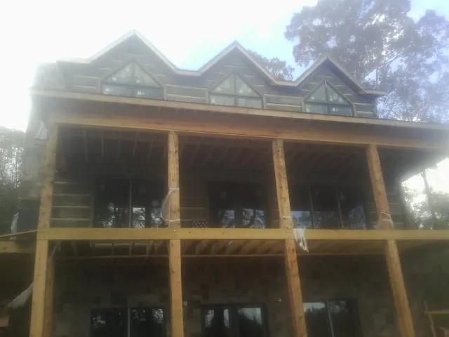 Dormers and porch framing on a large log home under construction — Roof Coating work by our crew in Baldwin Park
