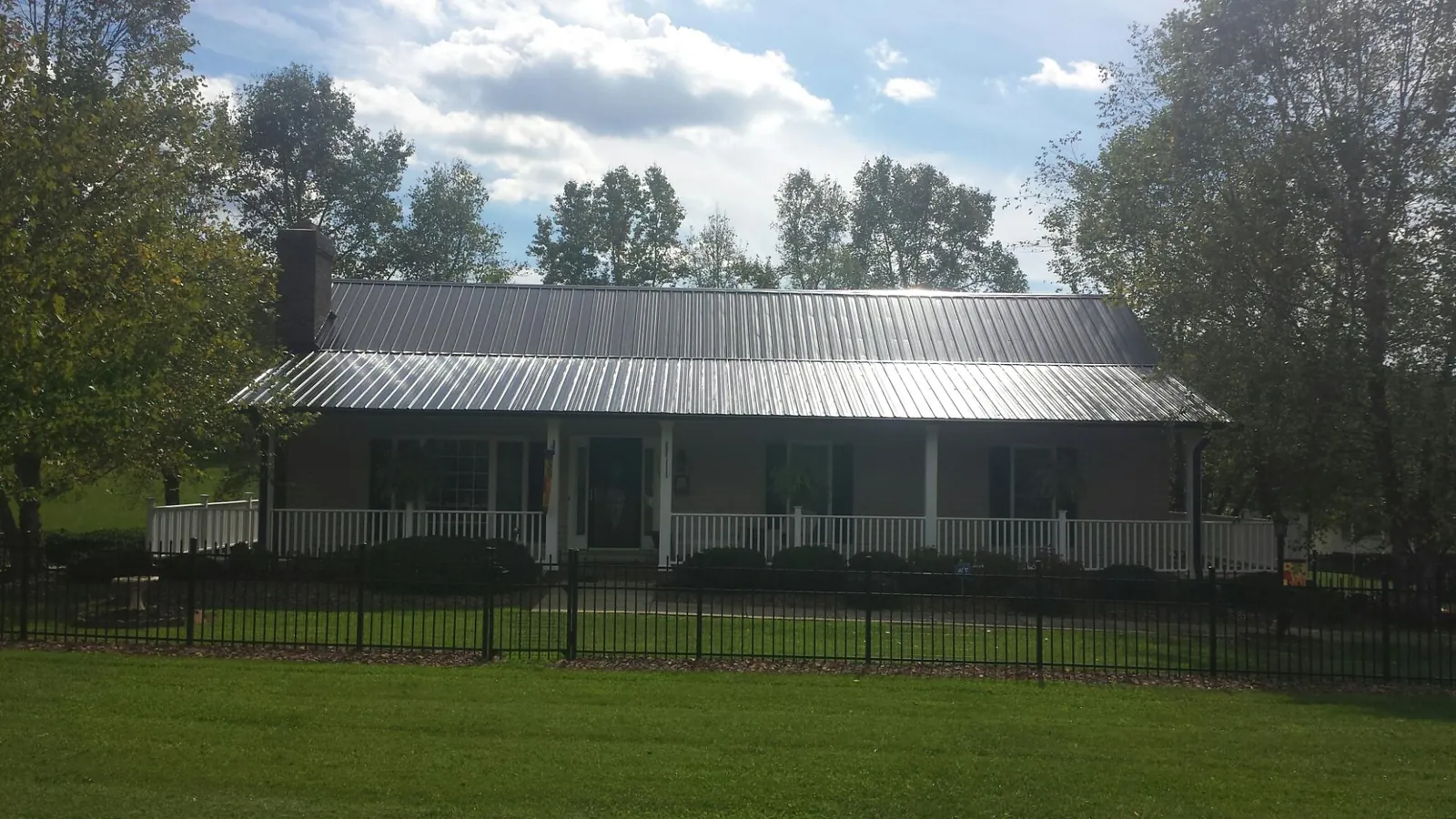 Gray metal roof on a brick ranch with a full width front porch — Gutter Guard Installation work by our crew in Baldwin Park