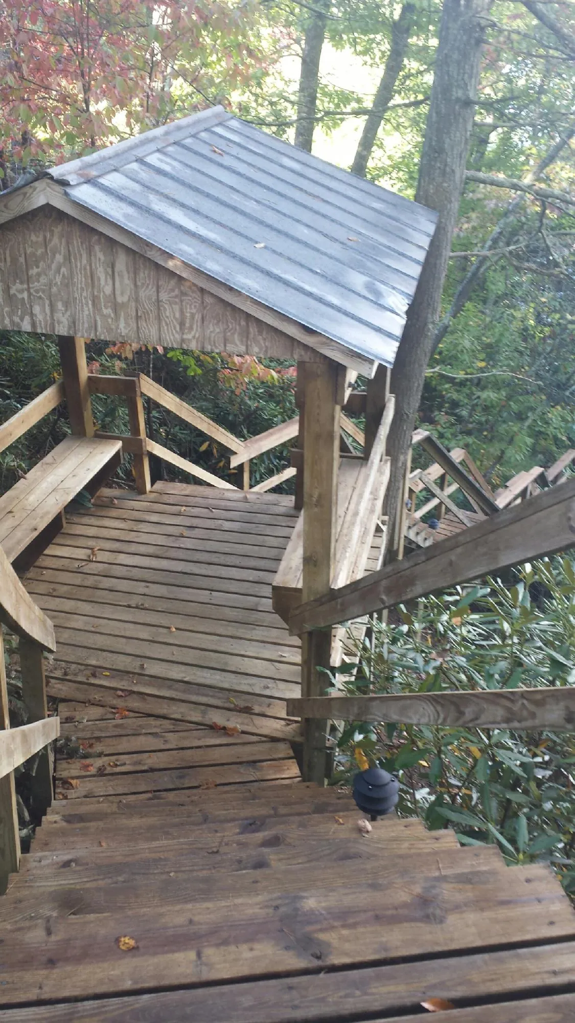 Metal roofed shelter over wooden steps on a wooded walkway — Skylight Repair & Installation work by our crew in Baldwin Park