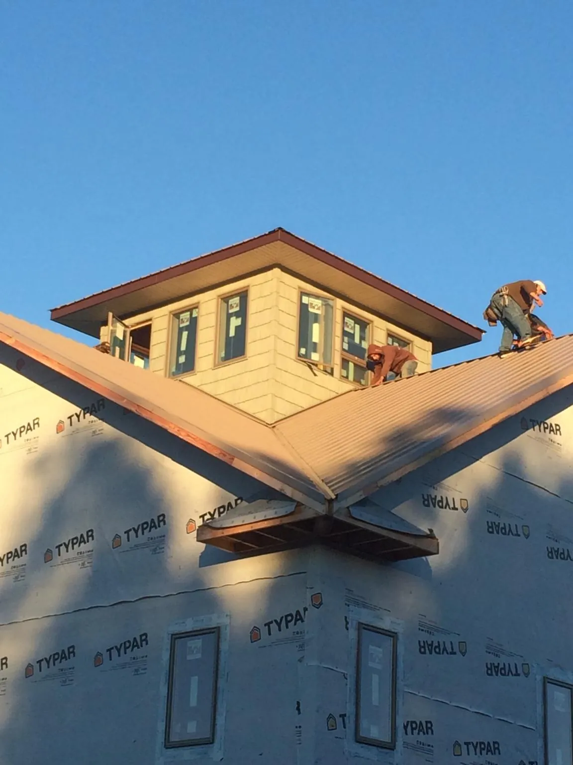 Roofers working around a rooftop cupola on a new metal roof at sunset — Roof Waterproofing in Baldwin Park by Roofing Brothers